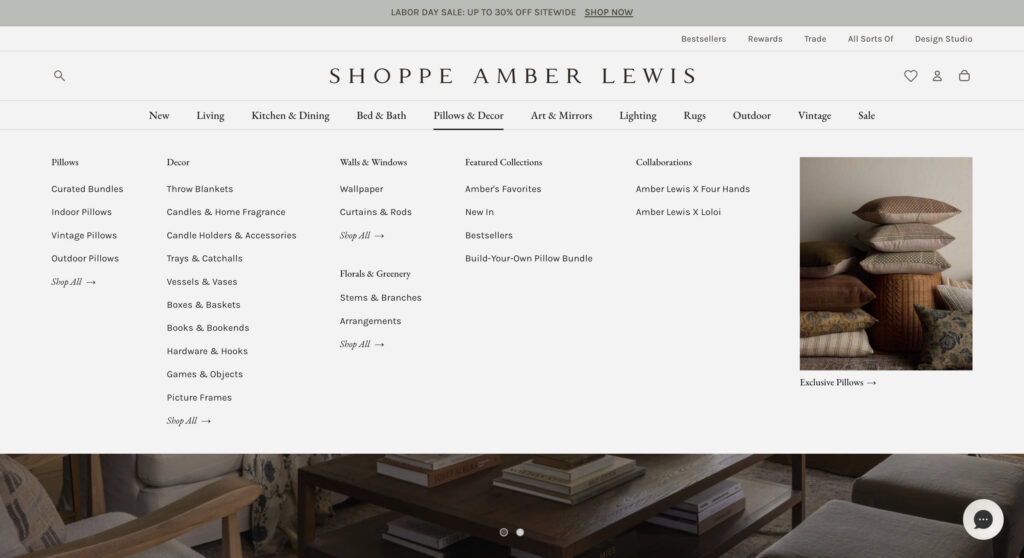 A desktop screenshot of the Shoppe Amber Lewis website mega-menu, demonstrating clean, organized navigation categories for pillows, décor, and home accessories.